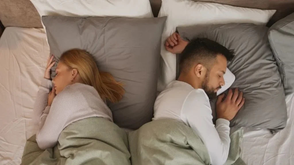 Ein Paar schläft Rücken an Rücken, symbolisch für gesunde Distanz und die Möglichkeit zur Heilung.

