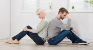 toxische Sexualität - dieses Bild zeigt ein Paar, Rücken an Rücken sitzend, symbolisch für die Distanz und den Konflikt, der oft in Beziehungen mit Machtmissbrauch entsteht