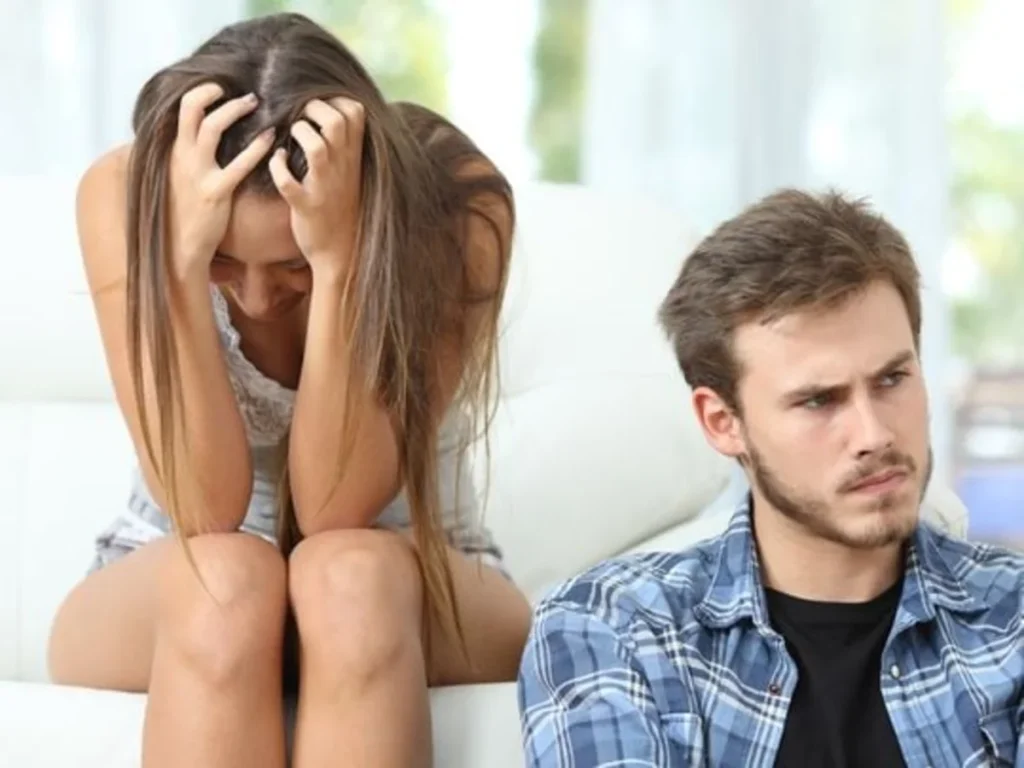 Ein Paar, das nach einem Streit wütend und traurig auf dem Sofa sitzt, symbolisiert eine schlechte Beziehungsdynamik.